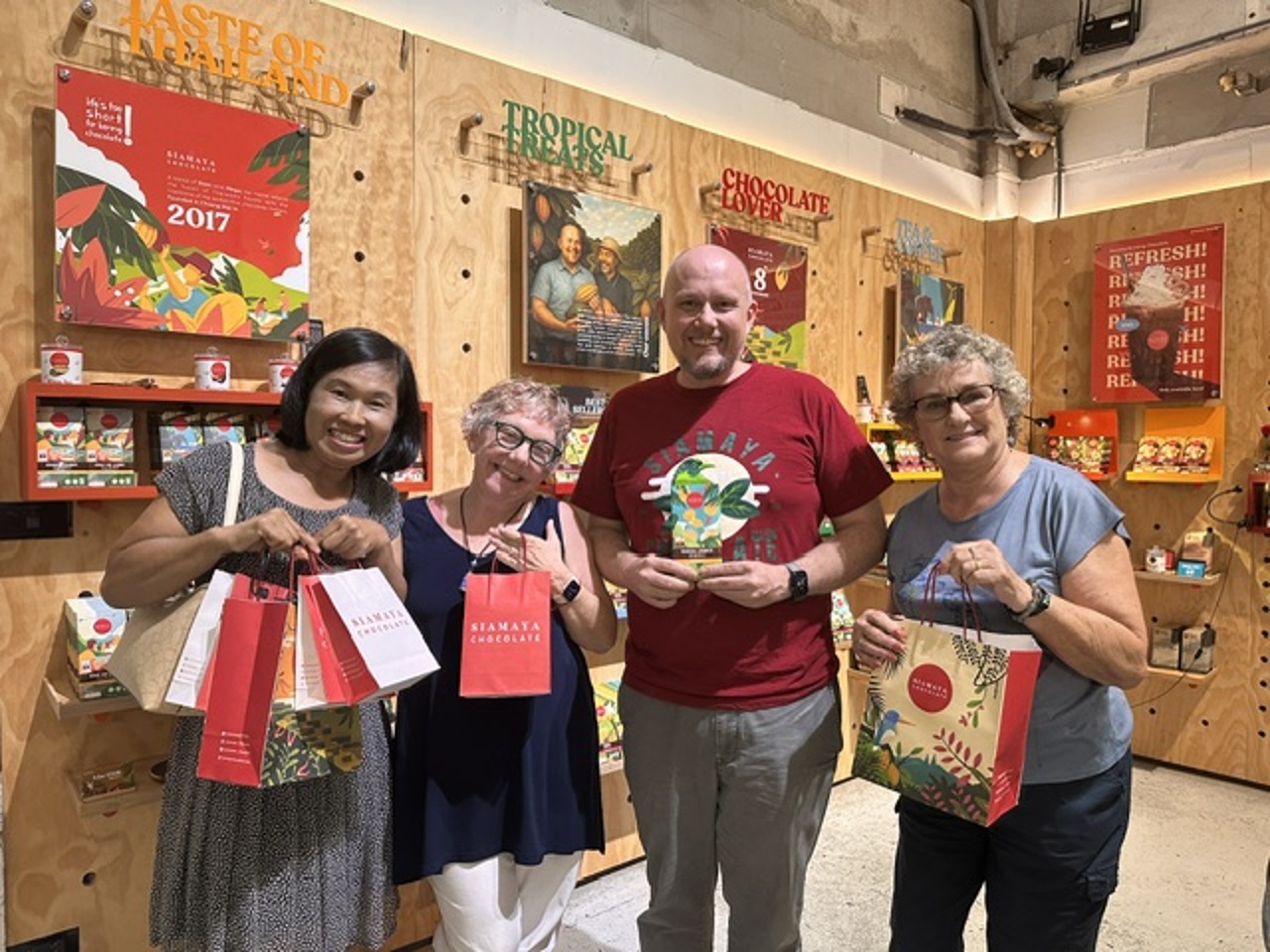 Smiling participants pose together holding their colorful Siamaya Chocolate shopping bags and custom bars.