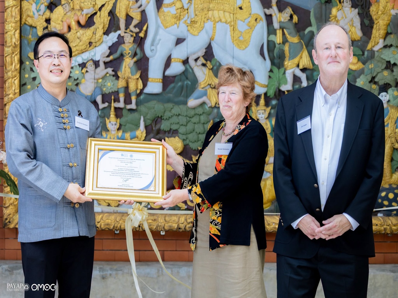 President Apicha Insuwan formally accepts the carved wooden mural from Nicole Simmons and Ambassador Eric Rubin during the dedication ceremony at the Lifelong Learning Center.