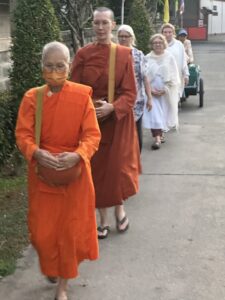 Buddhist nuns and lay followers on an alms round at Songdhammakalyani Monastery, Thailand