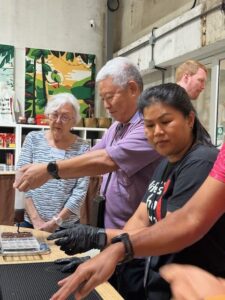 A group of people gathered around a counter, engaging in a chocolate-making activity at Siamaya Chocolate Factory, learning how to craft chocolate bars.