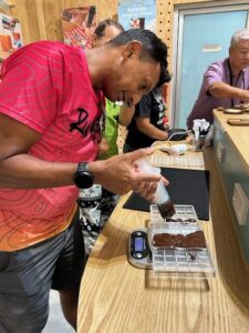 A participant is focused on creating their personalized chocolate bar with various flavors and ingredients at Siamaya Chocolate Factory.