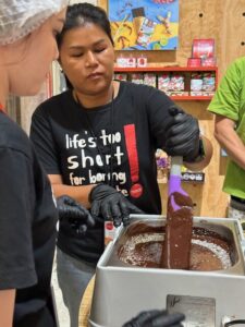 A staff member at Siamaya Chocolate Factory is carefully make chocolate , while another participant watches and learns.