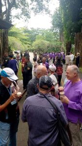 Participants of the Chiang Rai excursion enjoy a social moment during a cultural event, gathering in a vibrant outdoor space. Some are in traditional attire, while others are dressed in casual clothing, engaging in conversation and forming connections, symbolizing the blend of local culture and the international exchange fostered by the trip.
