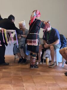 During the Chiang Rai excursion, a participant receives a traditional headpiece from a local community member dressed in colorful tribal attire. This moment highlights the cultural exchange between visitors and the local upland communities, where the traditions of craftsmanship and symbolism are shared.