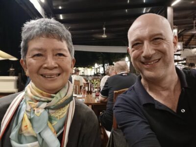 Two participants from the Chiang Rai excursion share a smile in a cozy setting, reflecting the camaraderie built throughout the journey. The image captures a moment of relaxation and connection, showing the bonds formed between participants as they explore the cultural and natural beauty of the region.