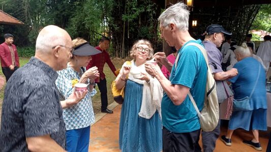 Participants of the Chiang Rai excursion enjoy a casual moment together, sharing a snack and engaging in friendly conversation. The image captures the warmth of the interaction, symbolizing the cultural exchange and camaraderie fostered throughout the trip as participants connect with each other and the local community.