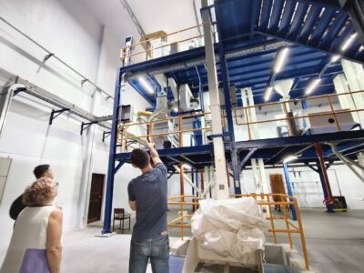 Participants tour the modern processing facility, viewing large-scale equipment used in cleaning and grading beans.