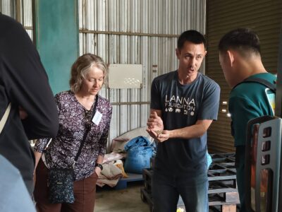The tour guide holds a handful of processed coffee beans while explaining quality control to interested participants.