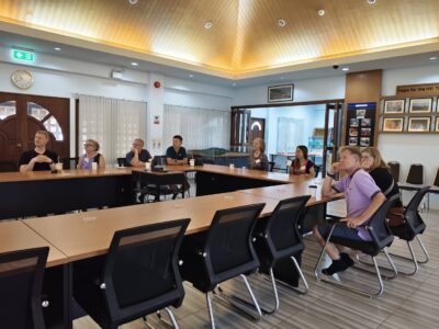 Lifelong Learning participants sit around a large conference table for an educational presentation on coffee farming and community development.