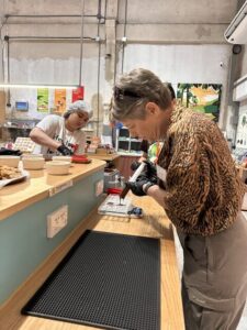A participant carefully uses a syringe to pipe melted chocolate into a plastic bar mold at the workstation.