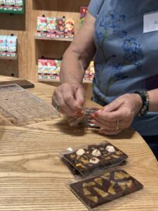 Close-up of a participant carefully wrapping their freshly set, custom-decorated chocolate bars in clear plastic.