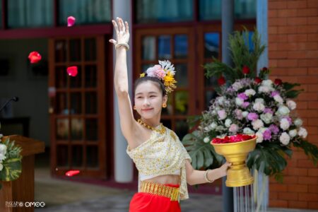 Traditional blessing dancer Mymint scatters flower petals during the dedication ceremony, welcoming guests with a Lanna cultural performance.